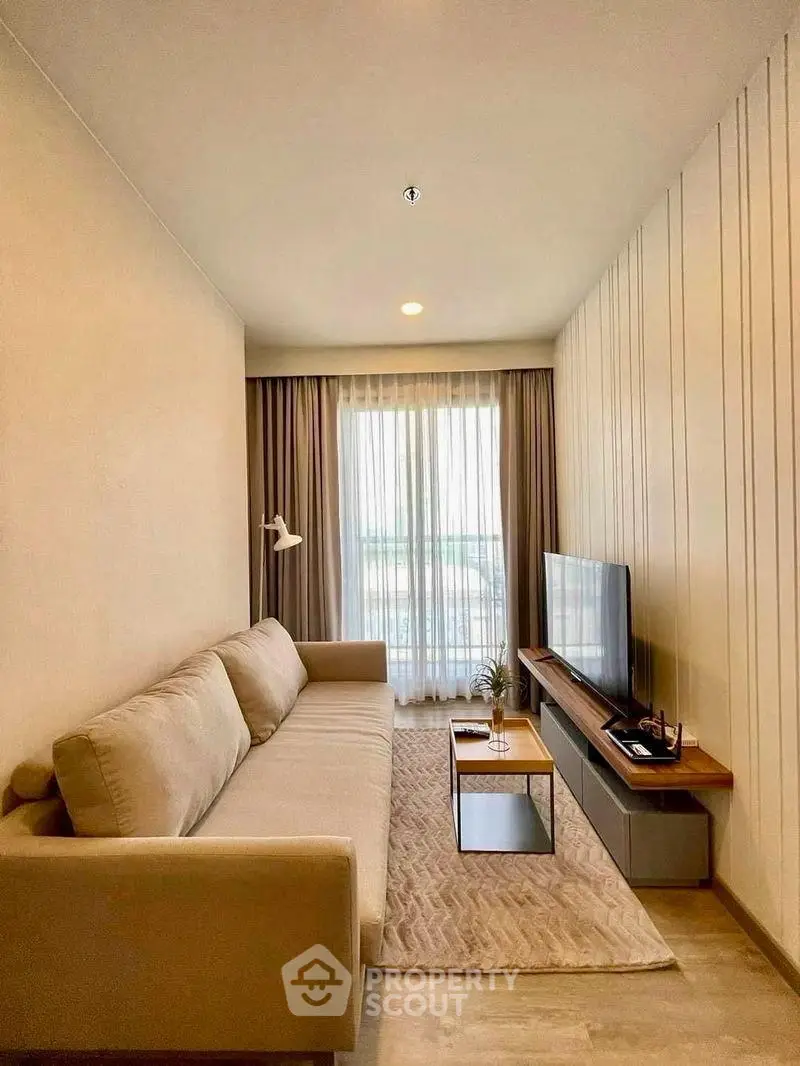 Modern living room with cozy beige sofa and large TV, perfect for relaxation.