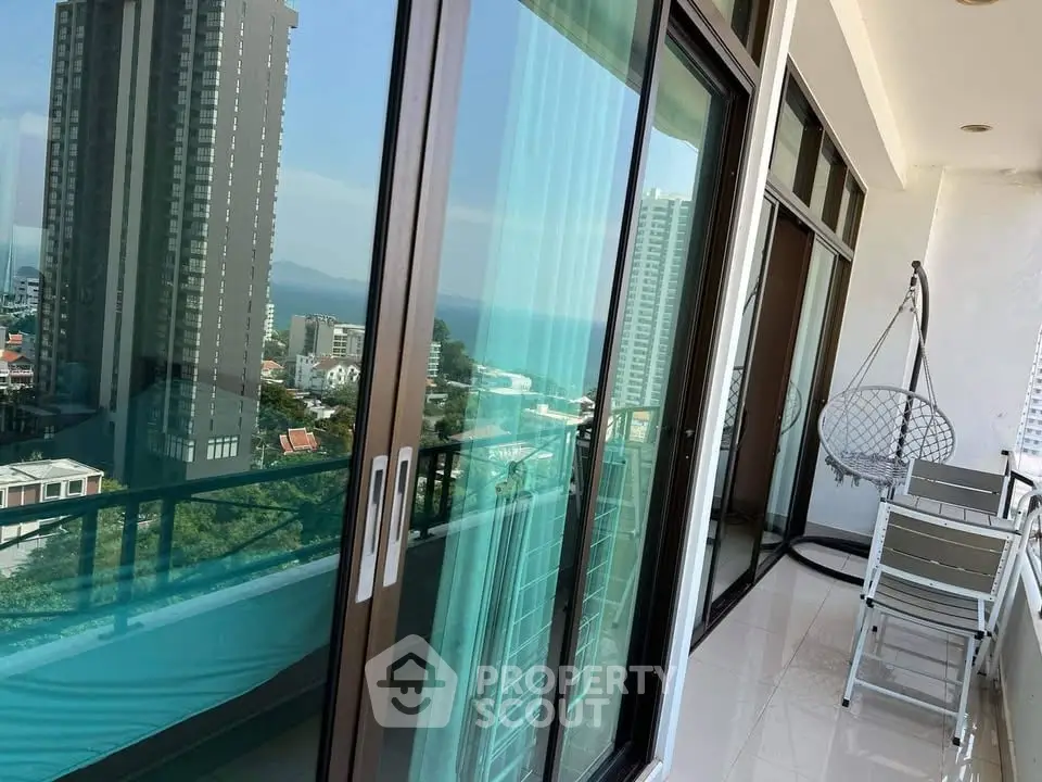 Luxurious high-rise balcony with stunning ocean view and modern seating area.