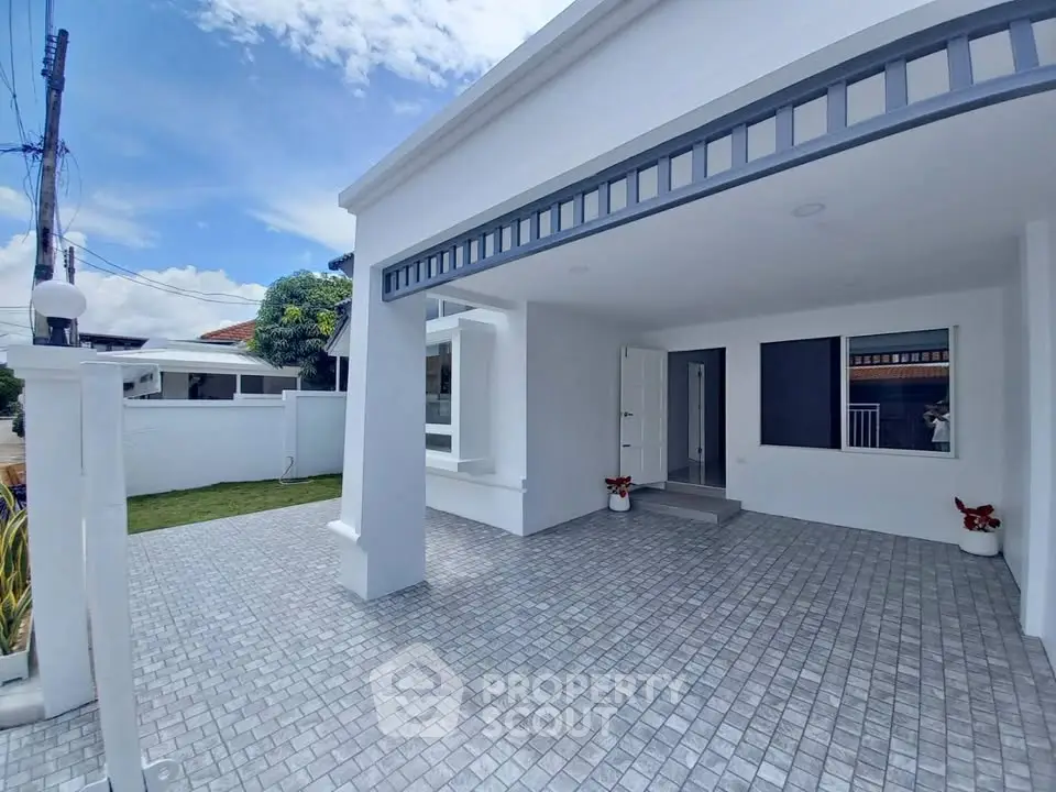 Modern white exterior of a house with spacious driveway and garden view.