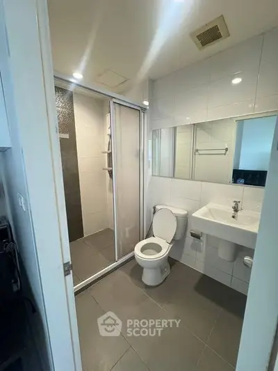 Modern bathroom with sleek design, featuring a glass-enclosed shower and contemporary fixtures.