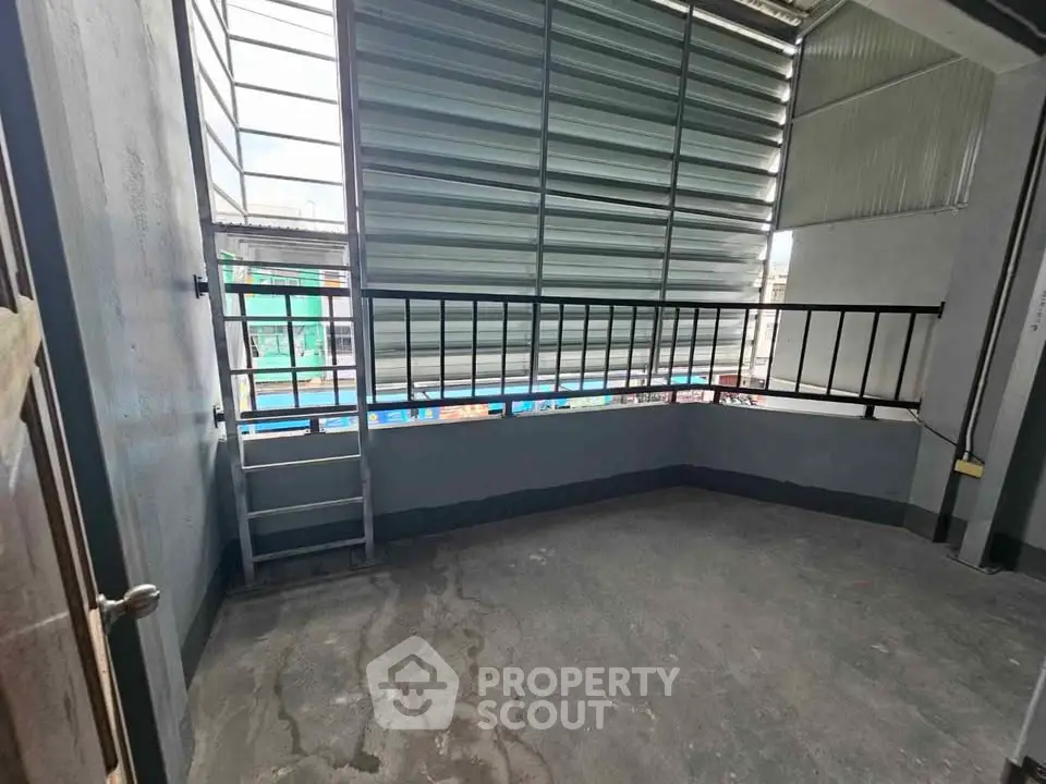 Spacious balcony with industrial-style metal railing and partial roof cover, ideal for urban living.