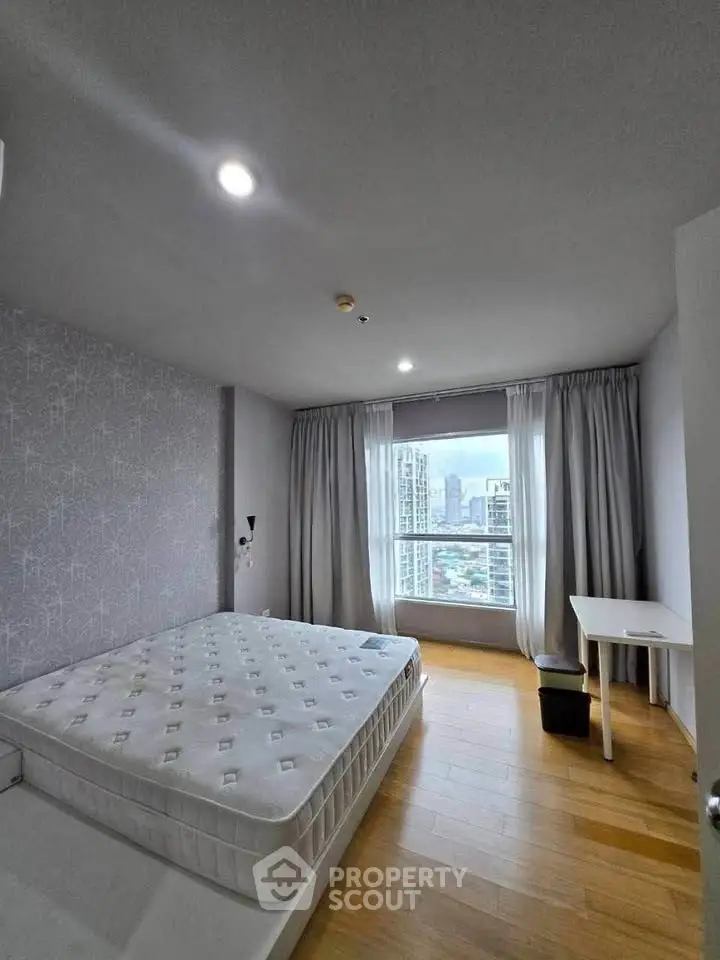 Spacious bedroom with city view, featuring a large window, modern decor, and ample natural light.