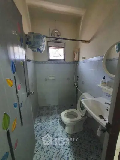 Compact bathroom with blue tile flooring and wall accents, featuring a toilet and sink.