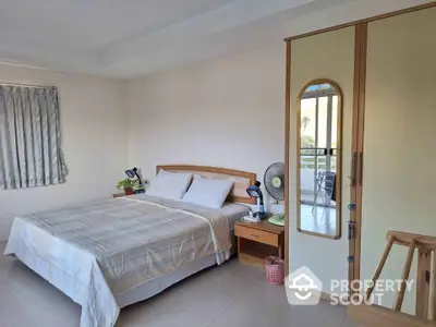 Spacious bedroom with ample natural light, featuring a large bed, wooden furniture, and access to a sunny balcony, ideal for a serene living experience.