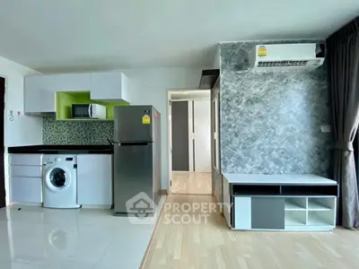 Modern apartment interior with kitchen and living area featuring washing machine and fridge.