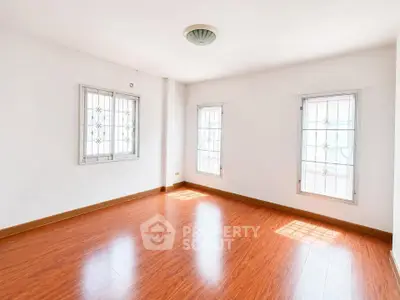 Spacious empty room with wooden flooring and natural light