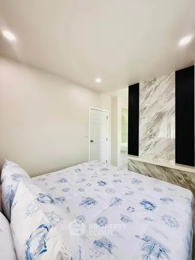Modern bedroom with nautical-themed bedding and marble accent wall