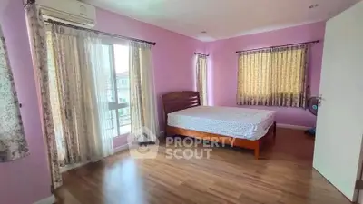 Spacious bedroom with wooden flooring and large windows in a modern home.