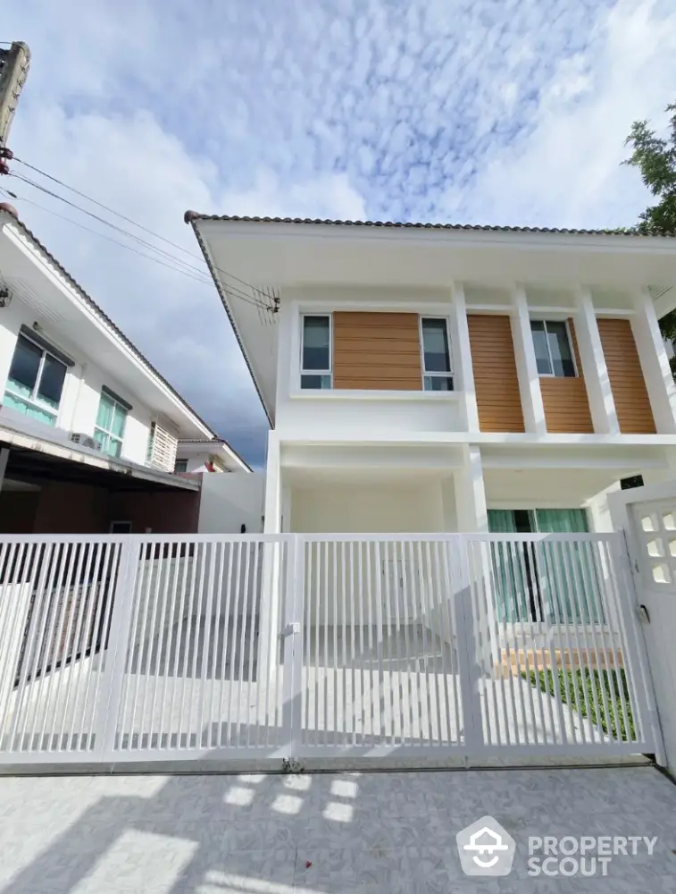 Modern two-story house with white fence and spacious driveway