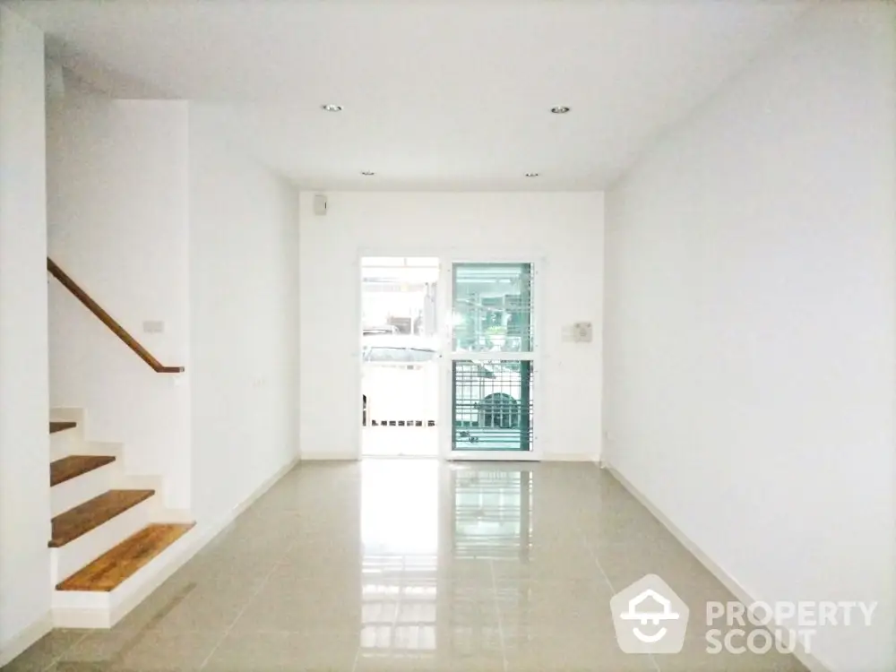 Spacious minimalist living room with glossy tiled floor and staircase