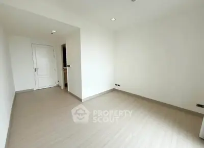 Spacious empty room with wooden flooring and white walls, perfect for customization.