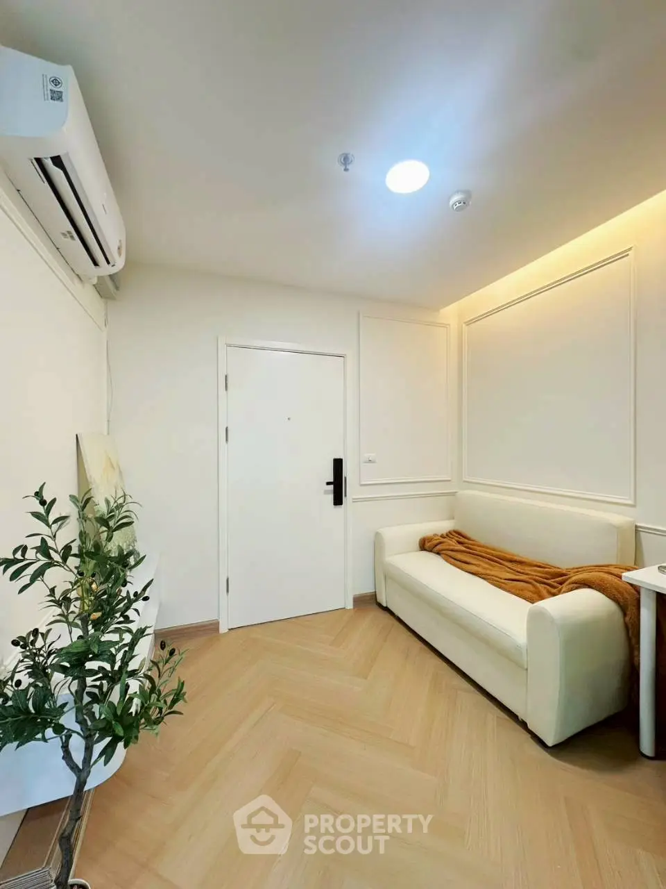 Modern living room with sleek white sofa and air conditioning, featuring elegant wood flooring and ambient lighting.