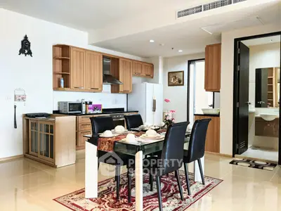 Modern kitchen with dining area, featuring wooden cabinets and elegant table setting.