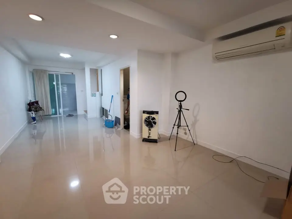 Spacious unfurnished living room with air conditioning and tiled flooring in modern apartment.
