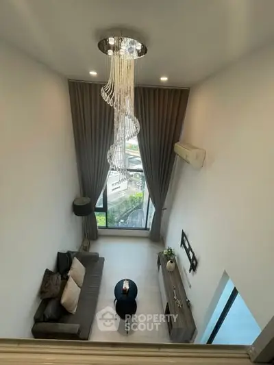 Luxurious high-ceiling living room with elegant chandelier and panoramic window view.