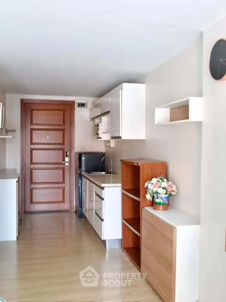 Modern compact kitchen with sleek cabinets and wooden accents in a cozy apartment.