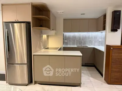 Modern kitchen with sleek cabinetry and stainless steel fridge in a cozy apartment.