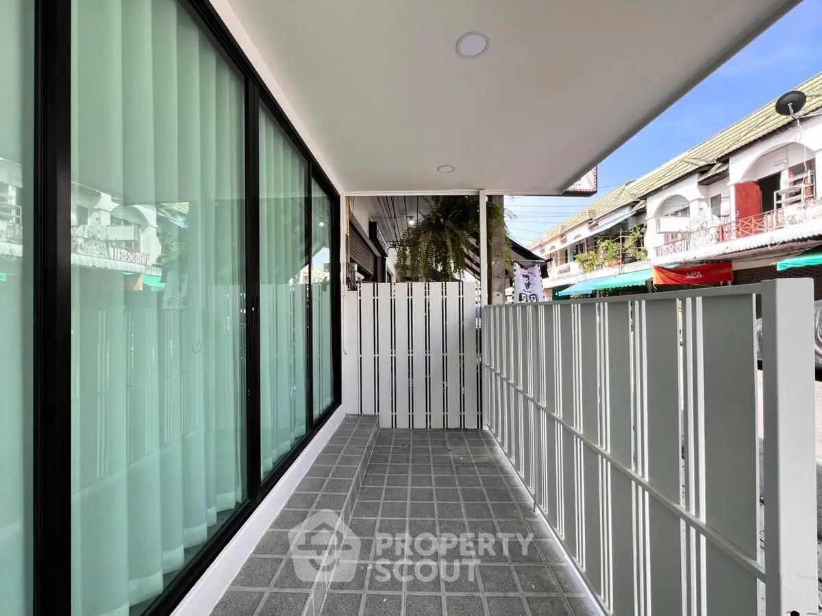 Modern balcony with sleek glass doors and privacy fence in urban setting.