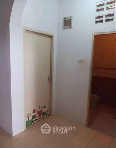Simple hallway with floral door and adjacent bathroom entrance