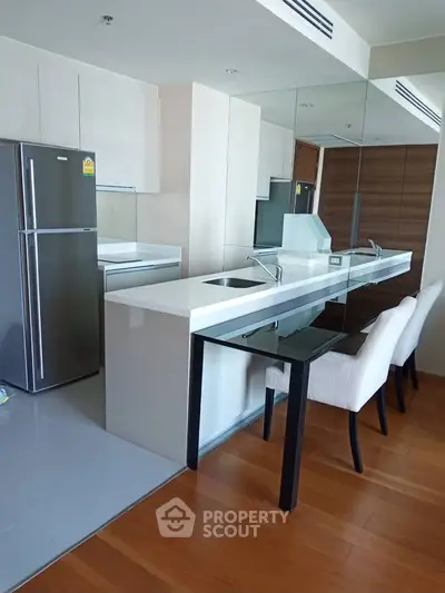 Modern kitchen with sleek design, featuring a large fridge and elegant dining area.