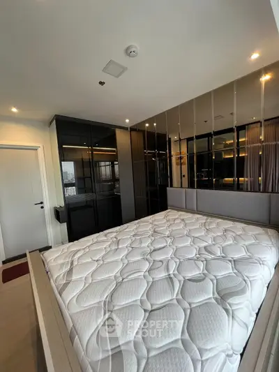 Luxurious bedroom with modern design and mirrored wardrobe in high-rise apartment.