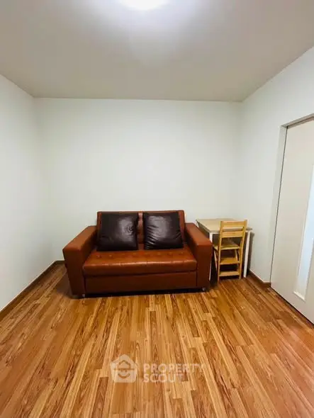 Cozy living room with brown leather sofa and wooden flooring, perfect for relaxation.