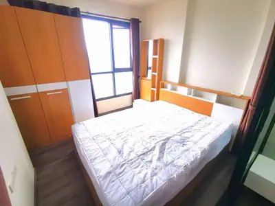 Modern bedroom with large window and wooden furniture, offering a cozy and bright atmosphere.