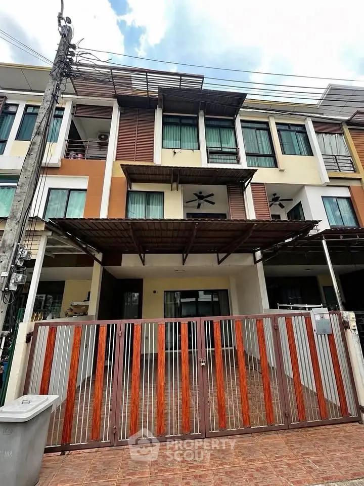 Modern multi-story townhouse with gated entrance and contemporary facade.
