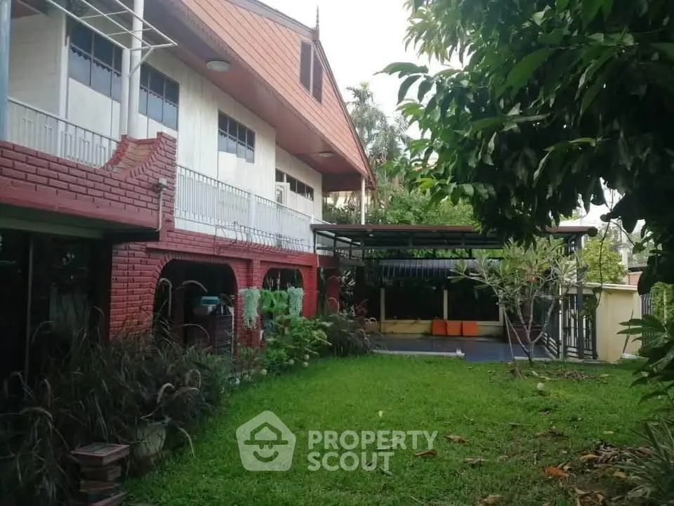 Charming two-story house with lush garden and spacious outdoor seating area.