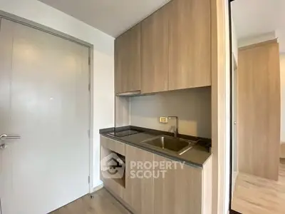 Modern compact kitchen with sleek wooden cabinets and stainless steel sink.