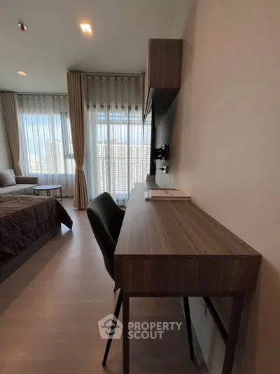 Modern bedroom with study area and large windows offering city views