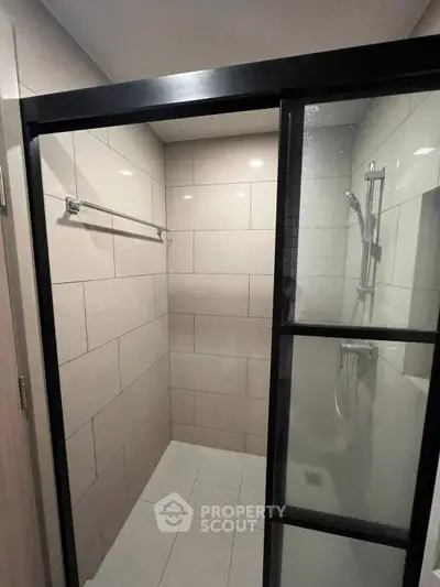 Modern bathroom with sleek glass shower enclosure and tiled walls.