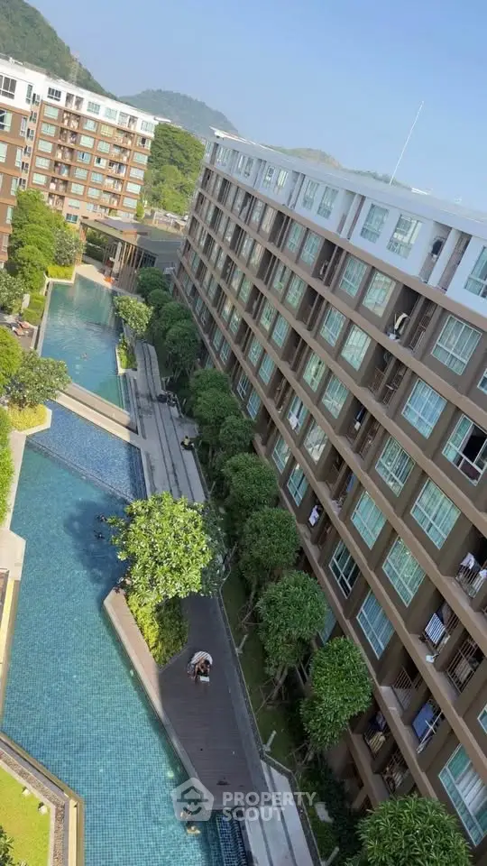 Modern apartment complex with pool and lush greenery, offering serene living environment.