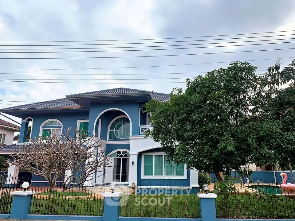 Stunning two-story blue house with lush garden and elegant architecture