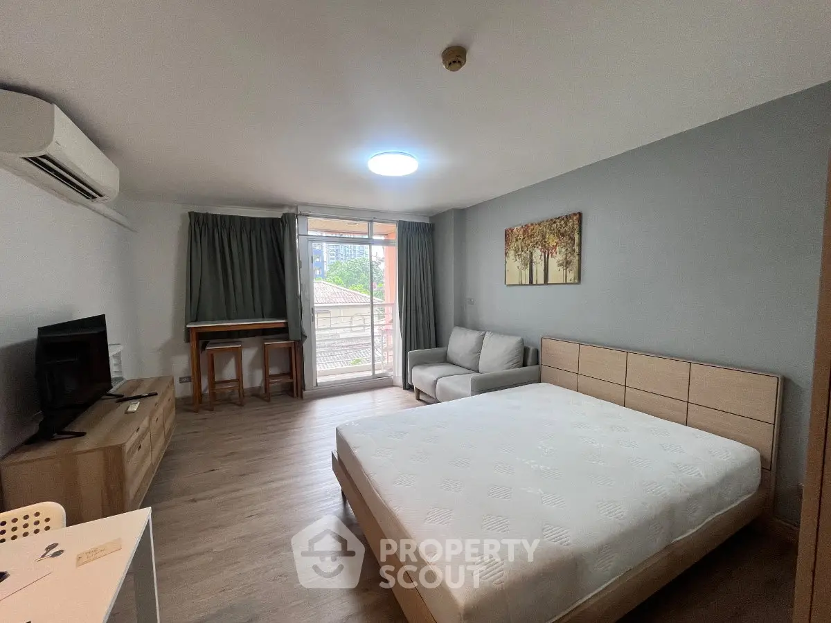 Spacious modern bedroom with balcony access and stylish decor in urban apartment.