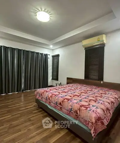 Spacious bedroom with wooden flooring and modern decor