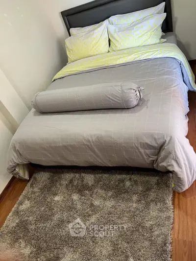 Cozy bedroom with stylish bedding and plush rug on wooden floor, perfect for relaxation.