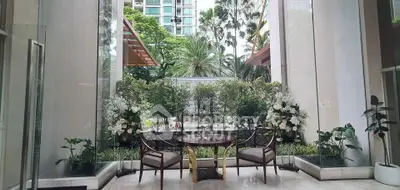 Luxurious building entrance with elegant seating and lush greenery, offering a serene and inviting atmosphere.