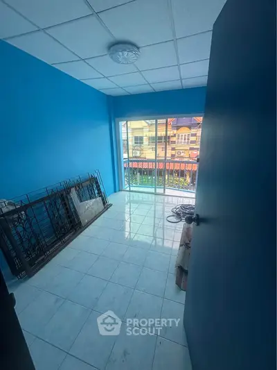 Bright blue room with large window and balcony view, ideal for customization.