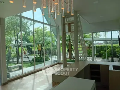 Spacious modern living room with large windows and garden view, featuring elegant lighting and open layout.