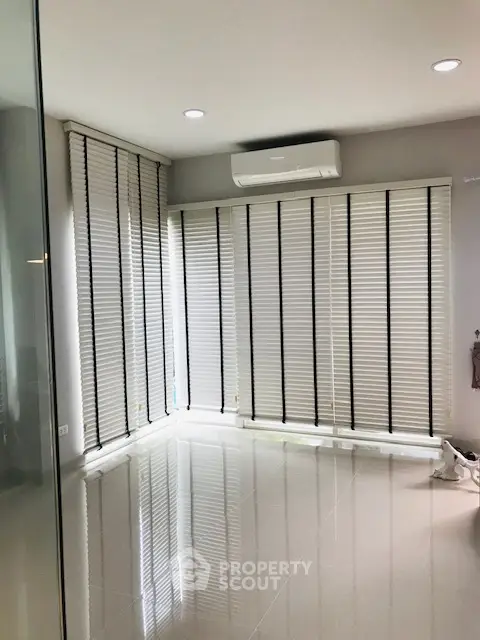 Bright corner unit with floor-to-ceiling windows and modern blinds