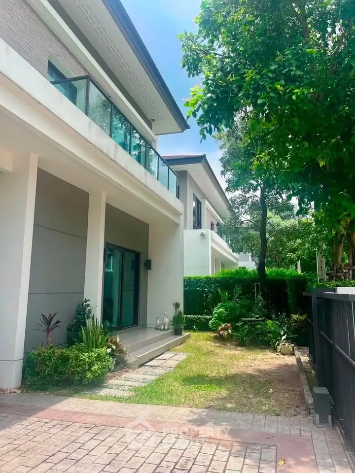 Modern two-story house with lush garden and spacious balcony, perfect for family living.