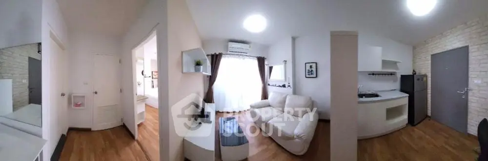 Modern open-layout living room with kitchen, featuring sleek furniture and natural light.