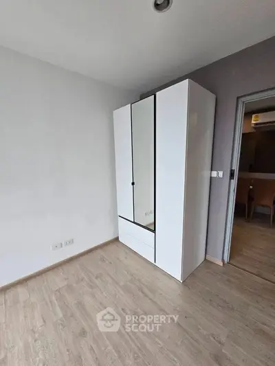 Spacious bedroom with sleek white wardrobe and modern wooden flooring.
