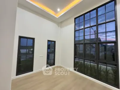 Spacious modern living room with high ceilings and large windows offering natural light.