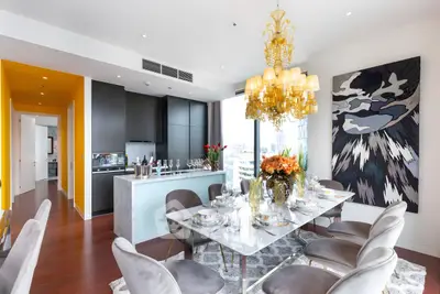 Luxurious dining room with elegant chandelier and modern open kitchen in high-rise apartment.