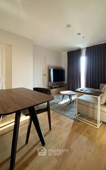 Modern living room with wooden flooring, stylish furniture, and a large TV, perfect for relaxation.