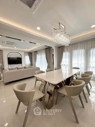 Luxurious open-plan living and dining area with elegant chandelier and modern furniture.