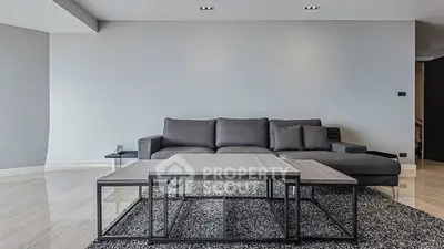 Modern living room with sleek gray sofa and stylish coffee table on a chic rug.
