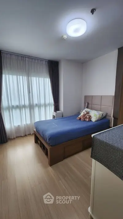 Cozy bedroom with large window and modern furnishings, perfect for relaxation and comfort.